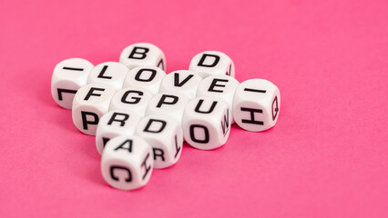 White letter dice forming the word “LOVE” on a vibrant pink background, symbolizing chance, gambling, and the unpredictability of life.