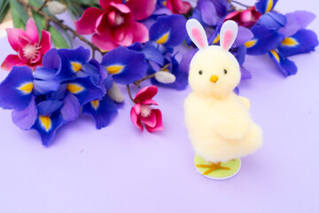 Easter scene with chiken in funny rabbit's ears, flowers in background.