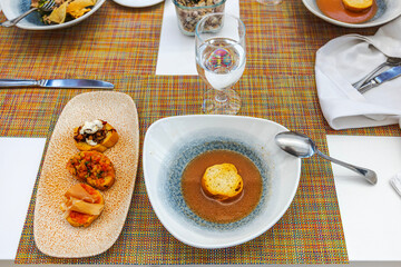 Elegant dining table with gourmet appetizers and soup served on colorful placemats. Mexico.