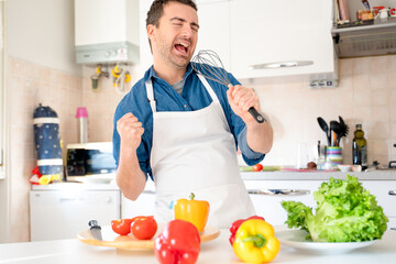 One man is singing in the kitchen while cooking