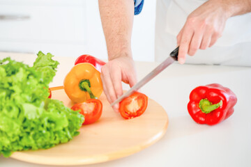 Close up of hand cutting vegetables on wooden cutting board