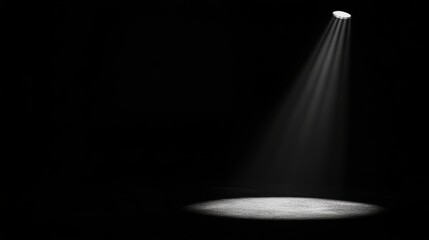 Moody black scene with a focused spotlight casting dramatic light and shadow on a textured floor