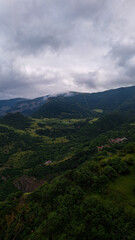 Fototapeta premium Foggy Mountain Valley with Dense Forest and Small Village