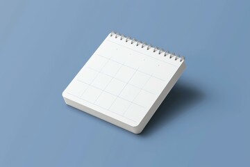 Blank page of a desktop calendar resting on a simple blue background, representing planning and scheduling