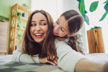 Joyful young mother and daughter playing together at home on a sunny spring day, enjoying relaxed moments and bonding.
