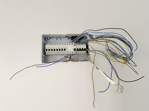 Electrical wiring panel under installation. Electrical wiring panel embedded in a wall during renovation, with exposed colorful wires hanging loosely