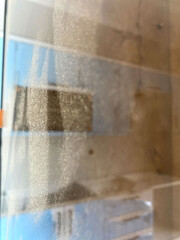 Dusty glass surface reflection. Vertical photo. Close-up of a dusty glass surface reflecting light...
