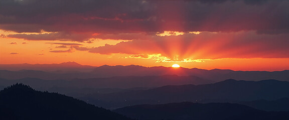 Fototapeta premium Vibrant rays of sunlight emerging from behind silhouetted mountain peaks during a dramatic sunset, casting warm orange and deep purple hues across the sky