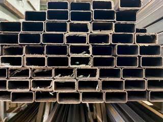 In a spacious warehouse, there is a towering stack of metal pipes meticulously arranged and stacked...