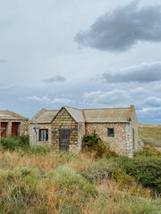 Obraz premium An old, sturdy stone house is comfortably sitting right in the middle of a vast open field, surrounded by natures beauty and tranquility, evoking a sense of peace and nostalgia