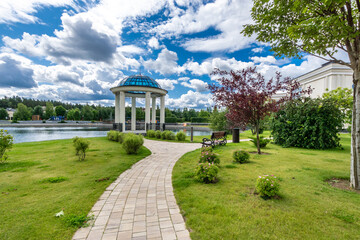 Obraz premium The amazing beauty of the landscape against the background of a blue sky with clouds. The .park area. Rotunda on the lake shore.