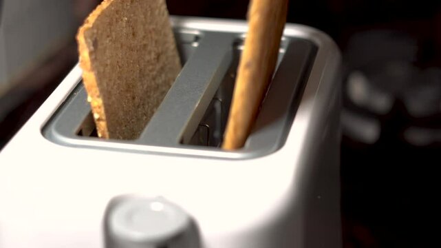 A person inserts sliced bread into a toaster, closeup. Real time
