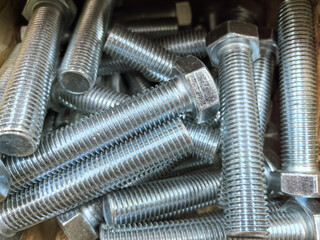 Metallic bolts and nuts piled together in a rustic workshop setting