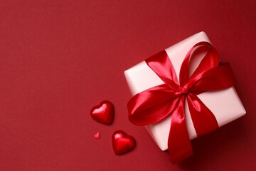 Beautiful gift box with hearts on color background