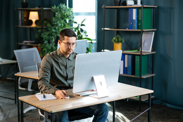 Young and confident businessman working in a modern office. Business man using computer.