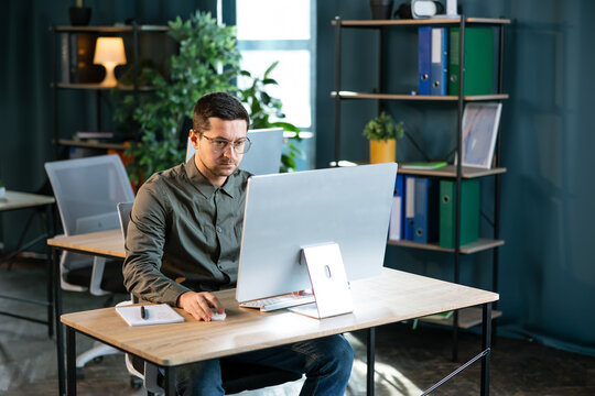 Young and confident businessman working in a modern office. Business man using computer.