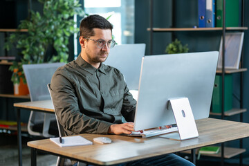 Obraz premium Side view portrait of modern IT developer using computer in office while working on VR games and software, copy space