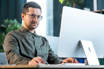 Confident young businessman working on computer at creative office