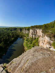A beautiful, winding river flows serenely through a picturesque valley that exists between two towering cliffs, creating a striking natural landscape that captivates all who behold it