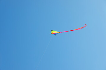 One colorful kite flying in blue sky