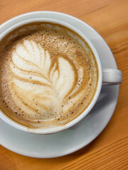 A creamy latte with perfect latte art served in Istanbul during a bright spring day. Capturing warmth and coziness with a wooden table backdrop