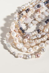 Pearl threads or necklaces on white background. Various natural pearl beads. Vertical