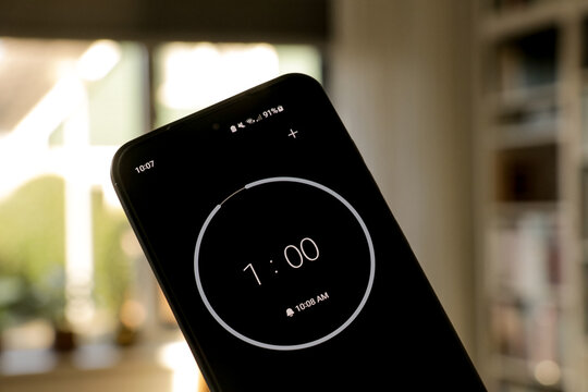 A phone with a black and white 1-minute timer to study with the pomodoro method on a blurry background