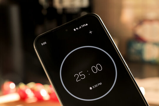 A phone with a black and white 25-minute timer for recipe cooking in kitchen with fresh food ingredients on a blurry background