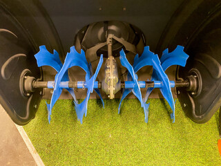 A snow blower is resting on top of a rich and vibrant green field, contrasting with the lush...