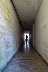 Silhouette of a woman standing at the end of a dimly lit hallway