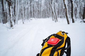 A yellow backpack with a first aid kit in it is sitting in the snow © Aleksey