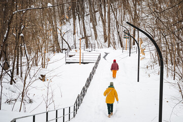 Two individuals are leisurely strolling down a picturesque snowy path that meanders through the...