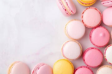 Obraz premium Colorful macarons in pink, yellow, and white tones on marble background, flat lay dessert composition, minimalistic French pastry design, pastel colors, copy space for text