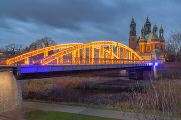 Fototapeta premium Illuminated bridge to the cathedral on Tumski Island at sunrise, Poznan, Poland
