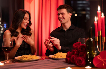 Handsome man making propose with ring to his surprised girlfriend while having date in romantic...