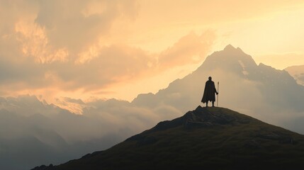 Silhouetted man on mountain peak at sunset, overlooking majestic mountains.