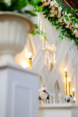 The decorations created for the engagement ceremony are white chairs, white decor fabric and yellow lights and artificial flowers.