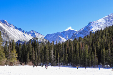 Frozen Bear Lake in Rocky Mountain National Park looking south. Hikers crossing the frozen lake on a cold March day.
