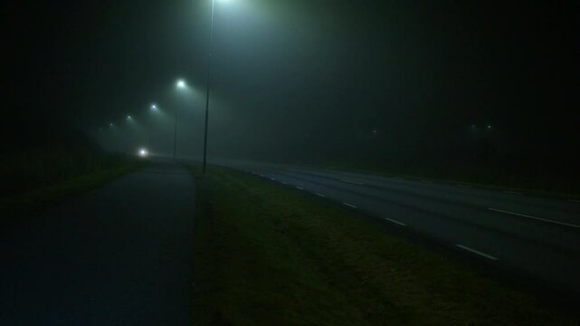 Cars driving down a foggy road at night