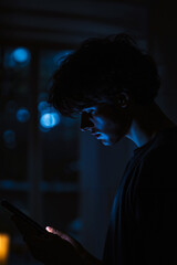 Obraz premium A man looking at his phone in the dark