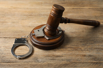 Handcuffs and judge's gavel on wooden table