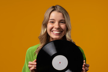 Pretty woman with vinyl record disc on yellow. Hobby, music lover, collection, nostalgia lifestyle.