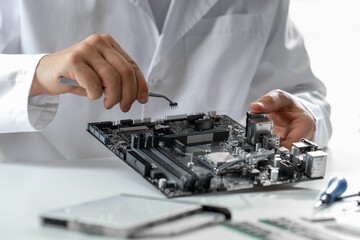 Man installing computer chip onto motherboard at white table, closeup