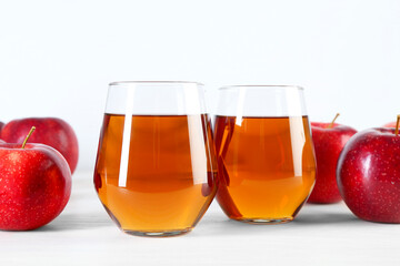 Fresh apple juice in glasses and fruits on white wooden table