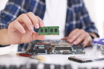 Man installing computer chip onto motherboard at white table, closeup