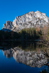 Lake Kreuzteich surrounded by mountain peak Pribitz in Hochschwab Alps in Tragoess, Styria, Austria. Forest in vibrant autumn foliage. Crystal-clear water reflects majestic ridges. Mirror-like effect