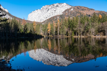 Lake Kreuzteich surrounded by mountain peak Messnerin in Hochschwab Alps, Tragoess, Styria, Austria. Forest in vibrant autumn foliage. Crystal-clear water reflects majestic ridges. Mirror-like effect