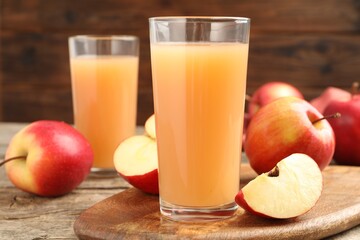 Tasty apple juice in glasses and fresh fruits on wooden table, closeup