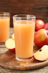 Tasty apple juice in glasses and fresh fruits on wooden table, closeup