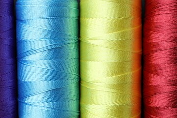 Spools of bright sewing threads as background, top view